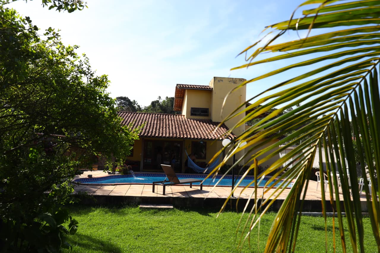 Jardim com casa e piscina ao fundo