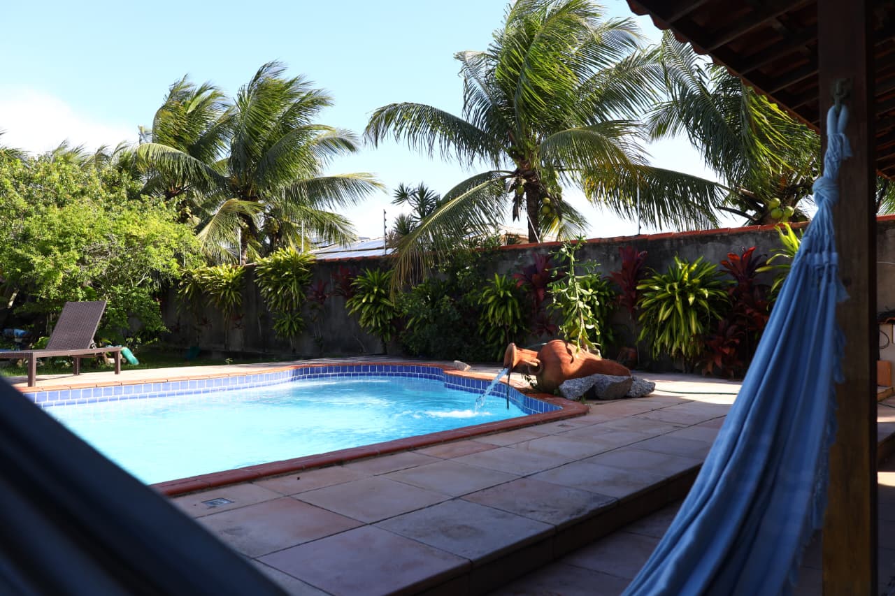 Área externa com piscina e jardim tropical